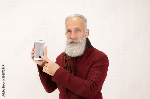 Portrait of a bearded senior man using his mobile phone against a white background.