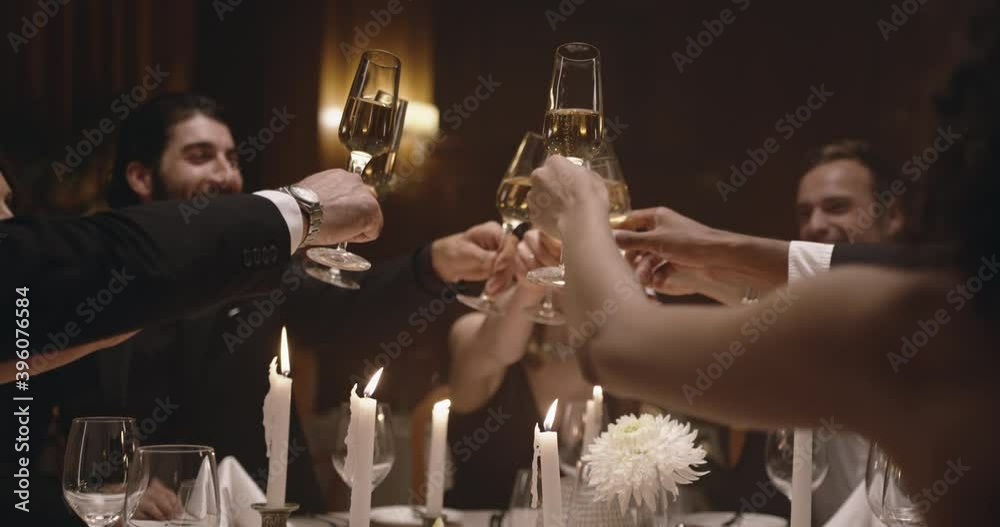 Group of people toasting drinks at a gala party. Multiracial friends enjoying new years party with drinks.
