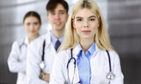 Group of three young doctors standing as a team with arms crossed in modern clinic and ready to help patients. Medicine concept
