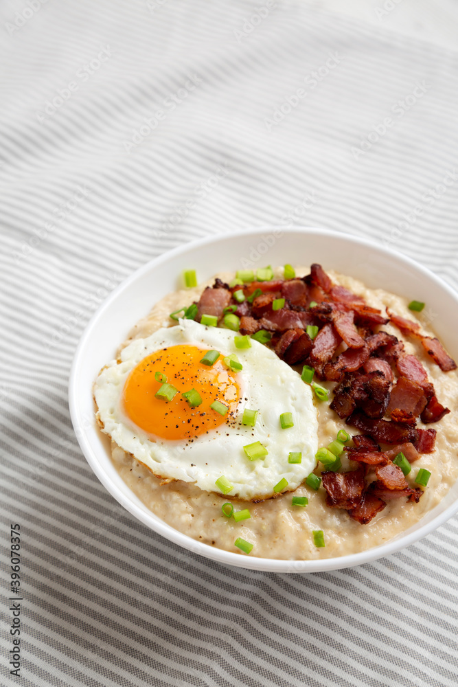 Homemade Cheesy Bacon Savory Oatmeal Bowl on cloth, side view. Copy space.