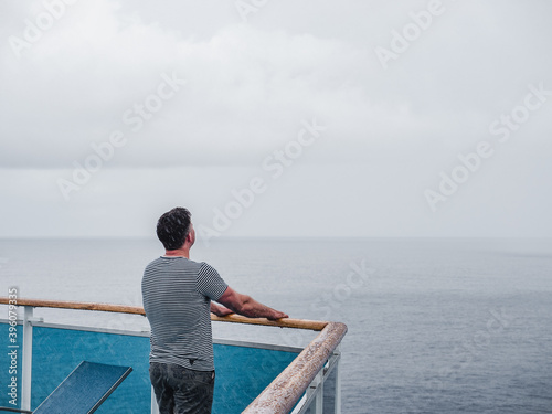Fashionable man on the empty deck of a cruise liner against a background of sea waves. Side view, close-up. Concept of leisure and travel