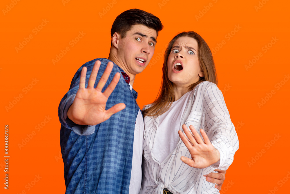 Fototapeta premium Shock, disgust and horror. Frightened young man and lady nervous fenced off with hands