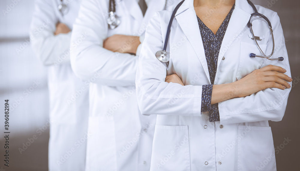 Doctors standing as a team with arms crossed in clinic. Medical help, insurance and medicine concept Doctors standing as a team with arms crossed in clinic. Medical help, insurance and medicine concept