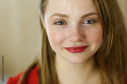 Head shot of a smart confident smiling millennial european woman standing with folded arms at home. Attractive young teenager student girl freelancer looking at camera  dressed in red