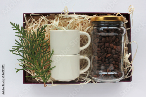 Christmas gift basket with coffee beans in glass jar and two espresso coffee cups. Corporate holiday gift box ideas. Present for family and friends. Top view
