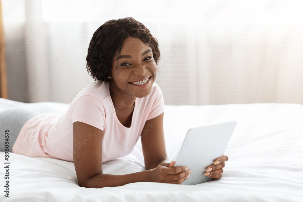 Smiling black woman using digital tablet in bed Smiling black woman using digital tablet in bed