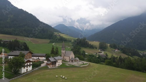 Reverse Aerial of Idyllic Church and Alps Backdrop, St. Magdalena, Dolomites, Italy photo