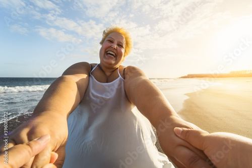 Happy overweight women having fun on tropical beach during sunset time