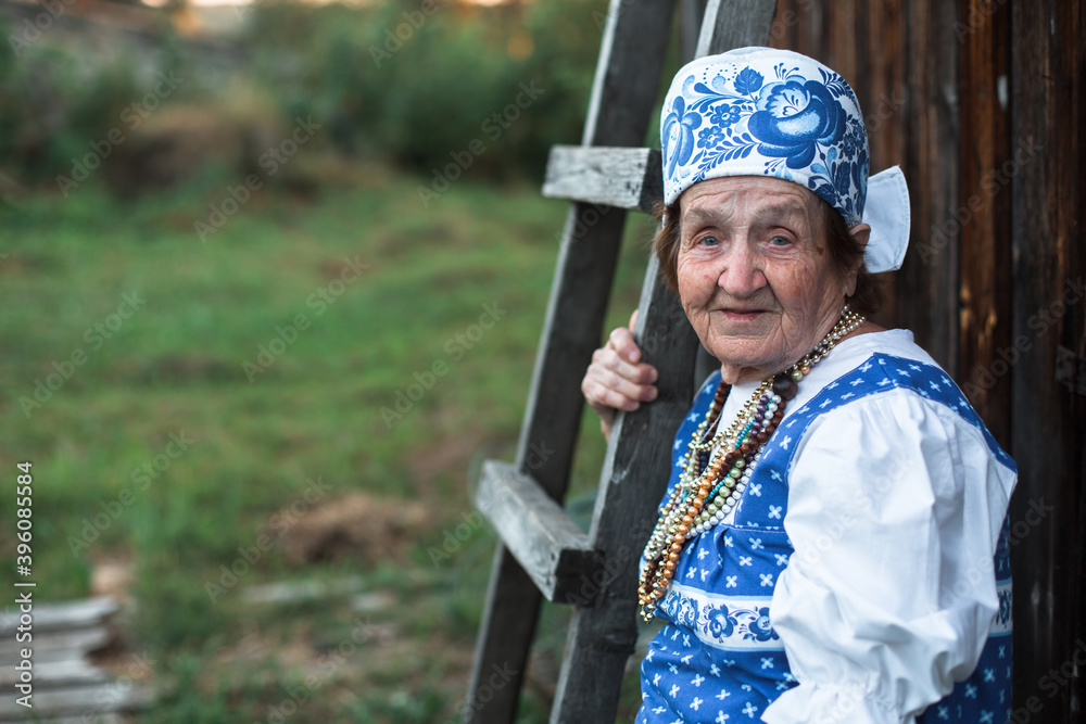 Portrait of an old woman in ethnic clothes, outdoors in the village. Portrait of an old woman in ethnic clothes, outdoors in the village.