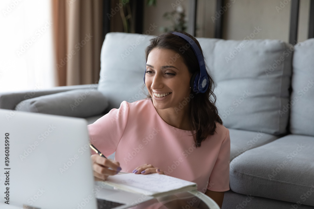 Happy young beautiful mixed race woman wearing headphones, enjoying online video call private educational class with teacher, studying foreign language distantly using computer software application. Happy young beautiful mixed race woman wearing headphones, enjoying online video call private educational class with teacher, studying foreign language distantly using computer software application.