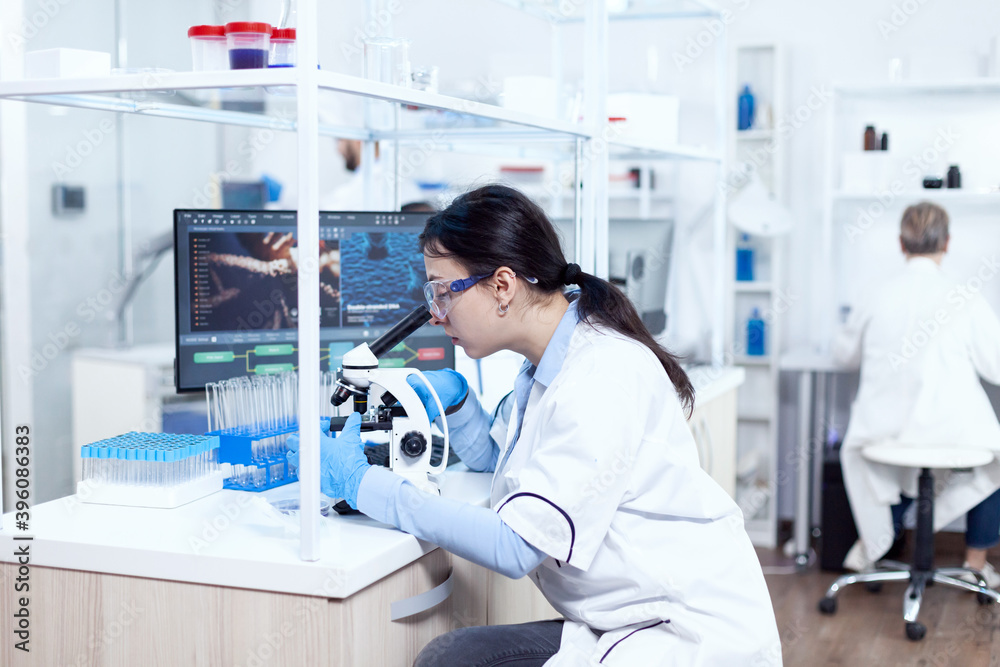Expert in genetics doing research using microscope to analise chemical ...
