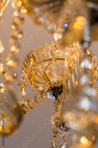 Chandelier of yellow crystal hanging with light energy saving bulbs.