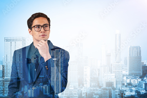 Young handsome businessman in suit and glasses dreaming about new career opportunities after MBA graduation. Bangkok on background. Double exposure. © VideoFlow