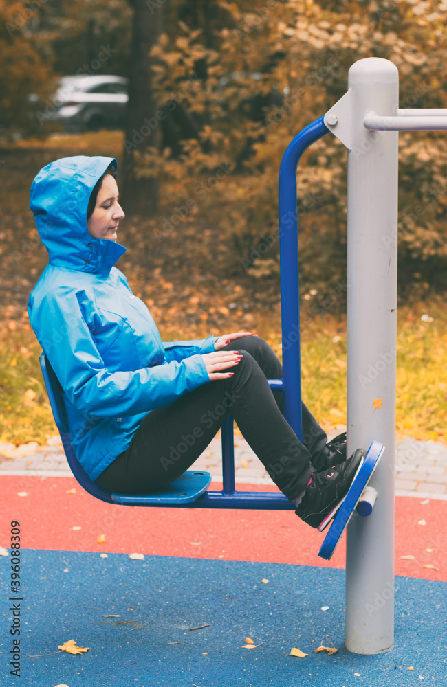 Fototapeta premium Young woman sitting bends her legs during an outdoor training session in Indian summer