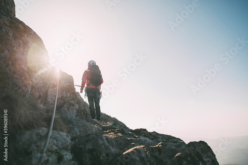 Fényképezés Rear view of mountaineer with backpack climbing along a via ferrata