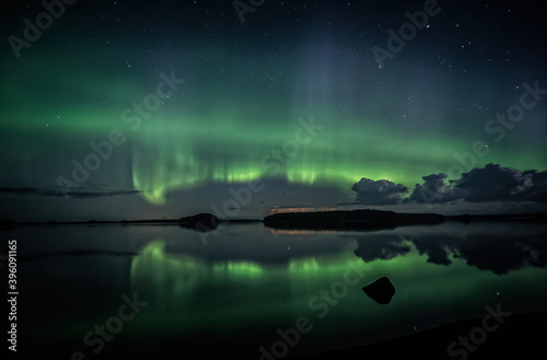 Northern lights dancing over calm lake in Farnebofjarden national park in north of Sweden.