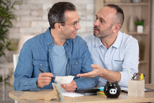middle-aged male couple doing paperwork at home photo