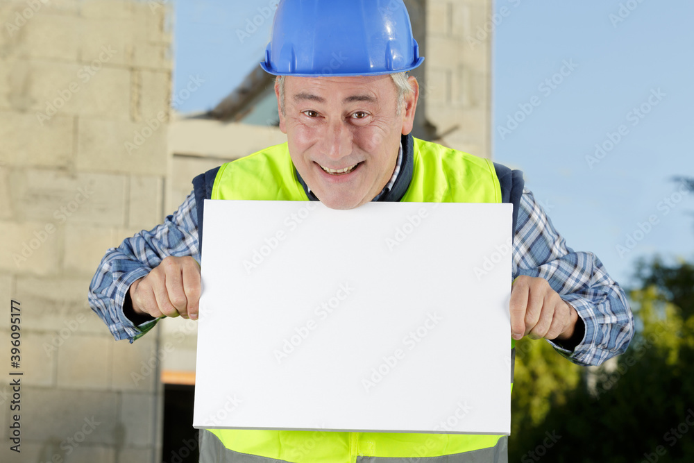 onstruction worker with protective hardhat and gloves showing blank banner
