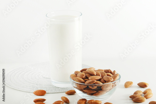 A glass with almond milk and the bowl with almonds