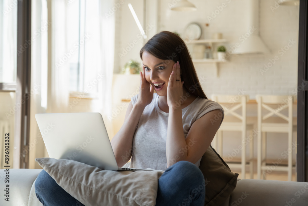 Overjoyed young woman with open mouth looking at laptop screen, reading good news in email, surprised excited female using computer, win online lottery, great shopping offer, sitting on couch at home Overjoyed young woman with open mouth looking at laptop screen, reading good news in email, surprised excited female using computer, win online lottery, great shopping offer, sitting on couch at home