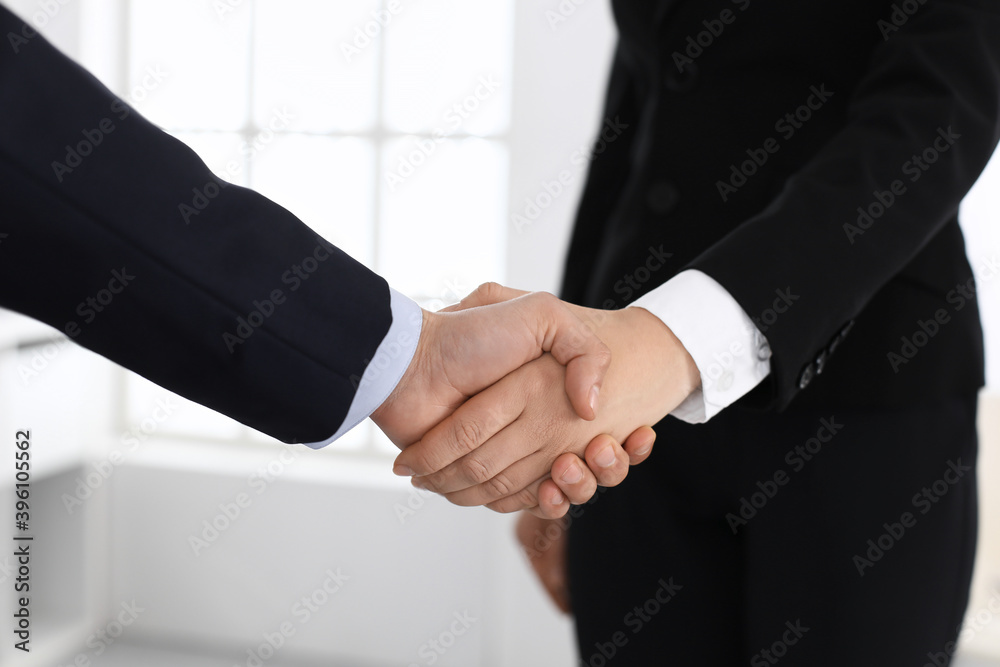 Businessman and woman shaking hands with colleagues at the background. Handshake at meeting in office. Concept of success in business Businessman and woman shaking hands with colleagues at the background. Handshake at meeting in office. Concept of success in business