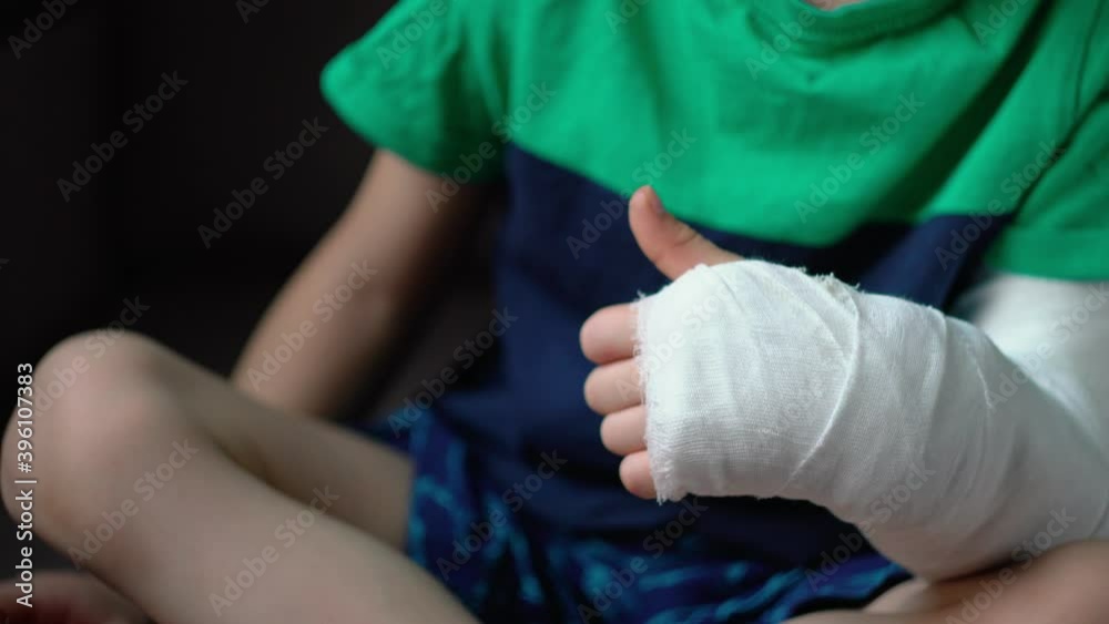 little boy lies on the bed with a fractured limb. a child's arm is broken. fracture injury. plaster cast on the arm little boy lies on the bed with a fractured limb. a child's arm is broken. fracture injury. plaster cast on the arm