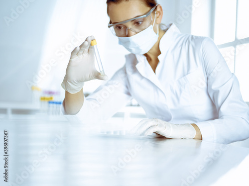 Female laboratory assistant analyzing a blood sample at hospital. Medicine  health care and researching concept