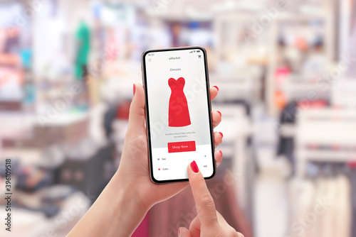 Girl buys a red dress with smart phone online. Clothing store in background concept