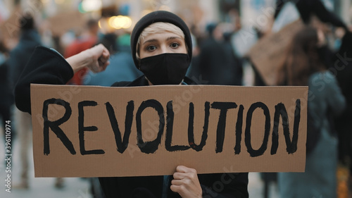 Revoultion concept. Young woman with face mask and banner protesing in the crowd. High quality photo