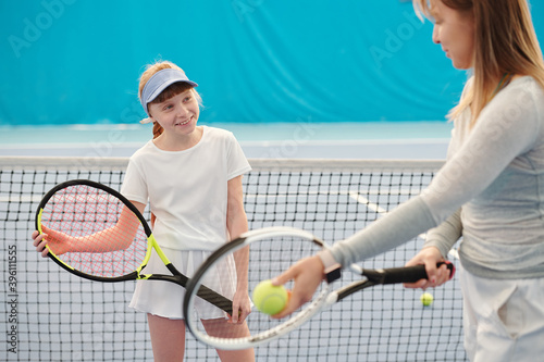 Active girl with tennis racket looking at trainer explaining how to use it © pressmaster