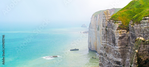 Misty morning fog at the rocky coastline in Normandy. Cliffs, panoramic view of Atlantic ocean, foggy morning