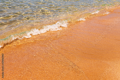 Calm morning sea beach with small waves with foam and clear water