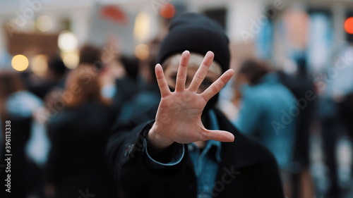 Stop. Young woman with face mask stoping camera with outstretched hand. Demonstation and protest. High quality photo