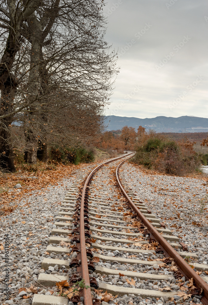 Fototapeta premium A small, railway station in the countryside at the foot of the mountains in an autumnal, overcast day (Greece, region Arcadia).