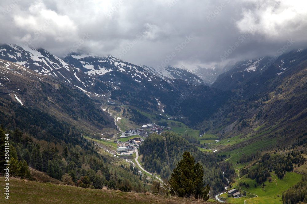 Fototapeta premium A village in the Alps among forests, against the backdrop of mountain peaks.