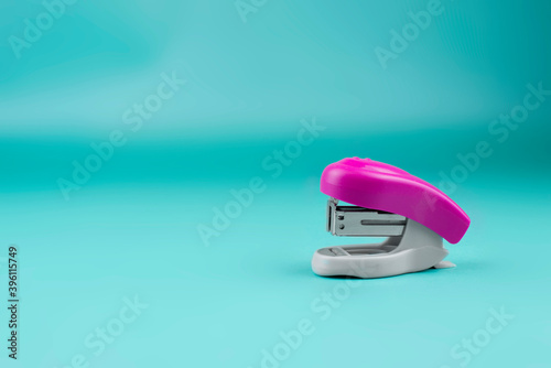 gray-pink stapler on a blue background. Bright stationery