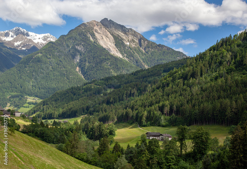 A village in the Alps among forests, against the backdrop of mountain peaks.