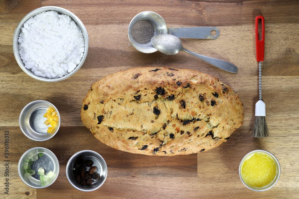 freshly baked traditional Saxon Christmas Stollen with some baking ingredients on wooden background freshly baked traditional Saxon Christmas Stollen with some baking ingredients on wooden background