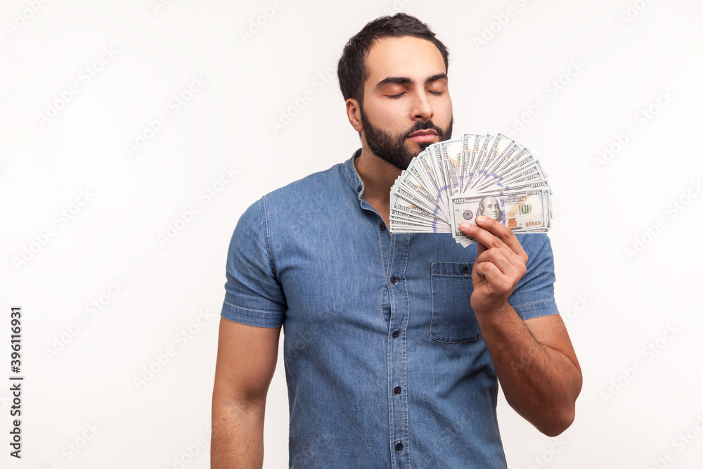 Mercantile bearded man enjoying smell of hundred dollar bills he holding, first big salary, reward for business idea. Indoor studio shot isolated on white background Mercantile bearded man enjoying smell of hundred dollar bills he holding, first big salary, reward for business idea. Indoor studio shot isolated on white background