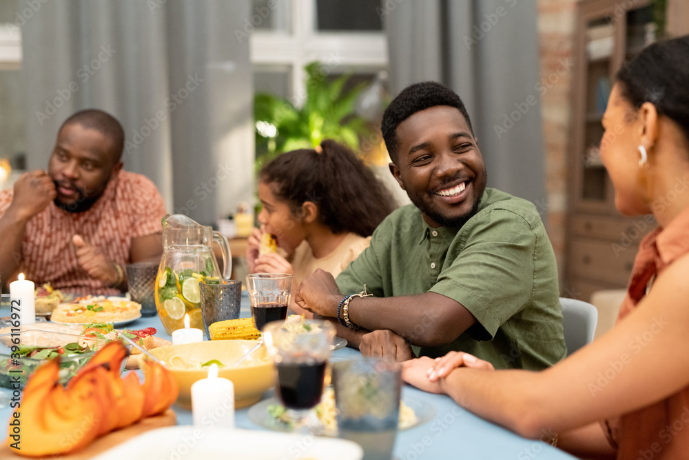 Happy young African man looking at his sister or girlfriend and talking to her Happy young African man looking at his sister or girlfriend and talking to her