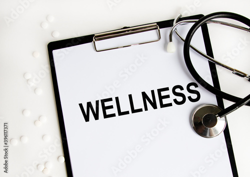 On the letter tablet is the text wellNESS, next to the white tablet and stethoscope.