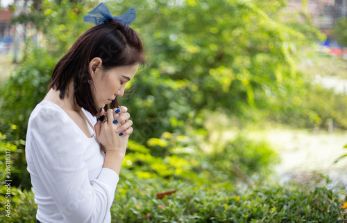 Bild auf Leinwand A woman in a white dress praying in the garden under the sunlight