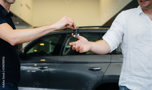 The seller passes the keys to a new car to a young family. Buying a new car © Andrii