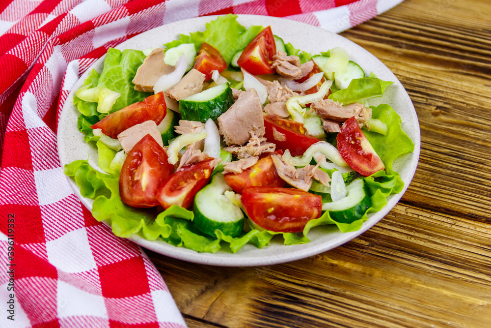Tasty tuna salad with lettuce and fresh vegetables on wooden table Tasty tuna salad with lettuce and fresh vegetables on wooden table