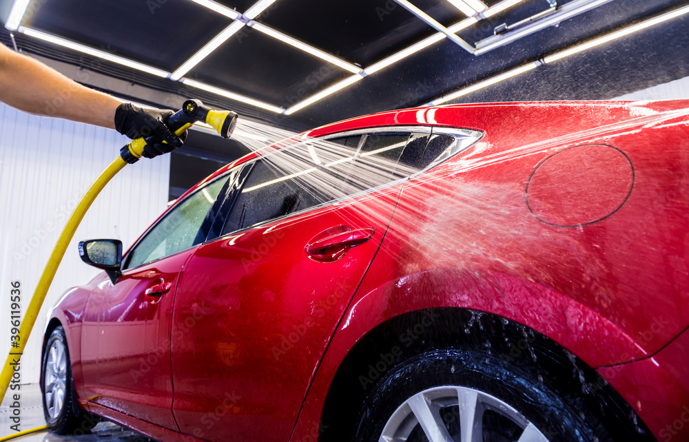 Service worker washing car on a car wash. Service worker washing car on a car wash.