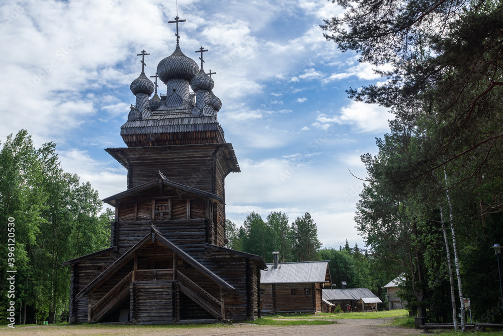 Old wooden orthodox church with a bell tower against the blue sky. Traditional ancient architecture of the north of Russia