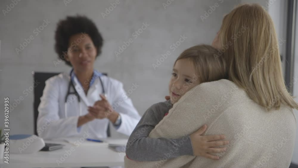 Mother with her little daughter at the pediatrician examination by African american female doctor Mother with her little daughter at the pediatrician examination by African american female doctor