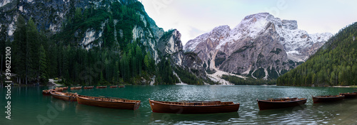 A panoramic view of the lake Pragser Wildsee in the Dolomites with a chain of boats  mountains and woods in autumn in South Tyrol  Italy.