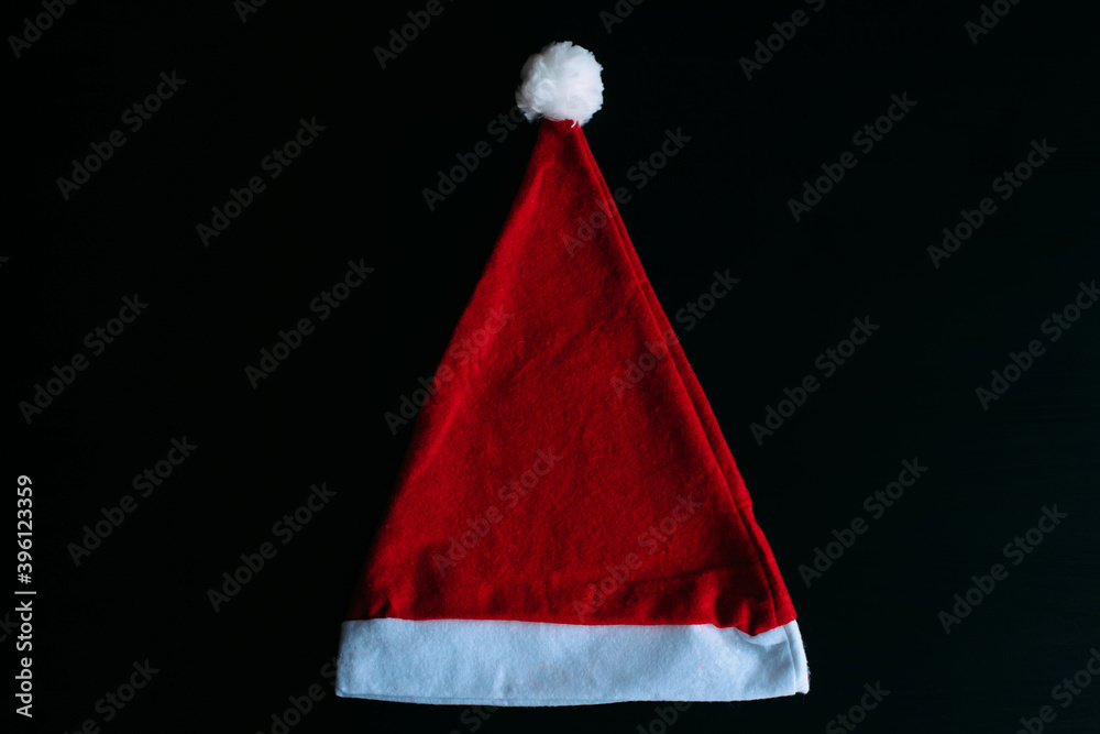 Red Santa Claus hat isolated on black background, top view. Father Christmas cap, close up. New year holidays concept. Red Santa Claus hat isolated on black background, top view. Father Christmas cap, close up. New year holidays concept.