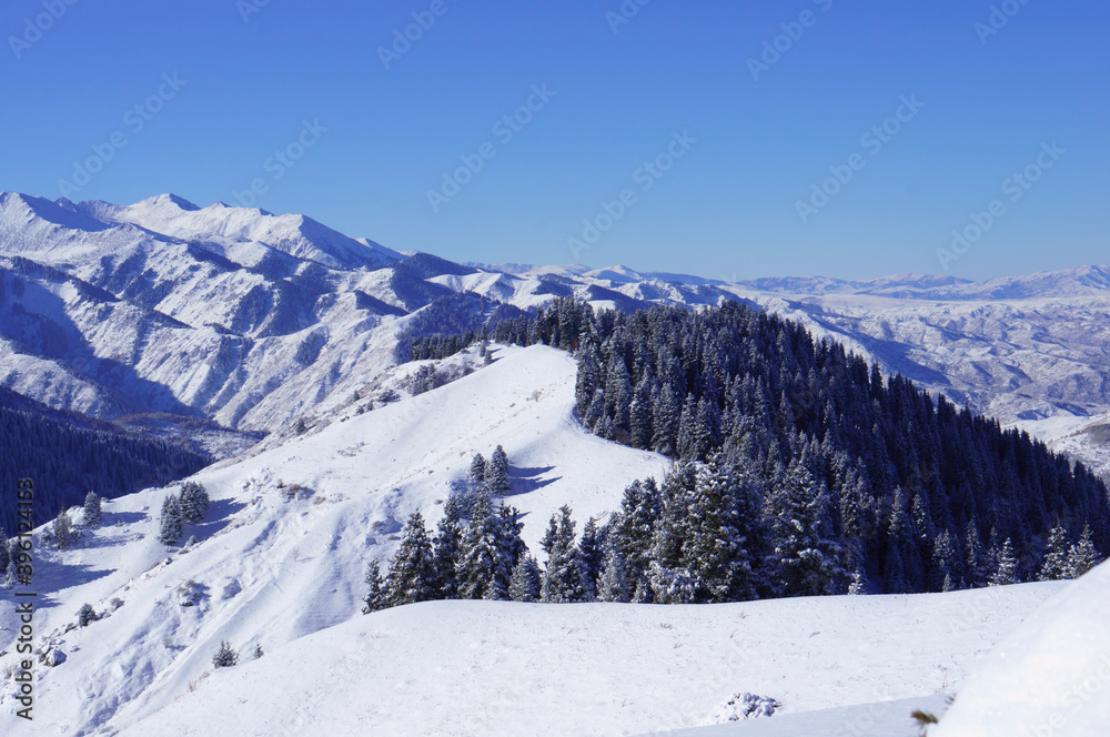 A mountain range stretching into the distance. A mountain range on one side without trees. Beautiful alpine winter landscape. Snowy mountains. Highlands.
